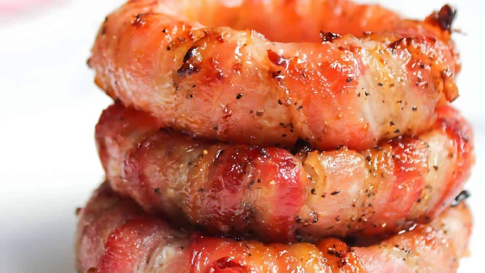 Three stacked, crispy bacon-wrapped onion rings.