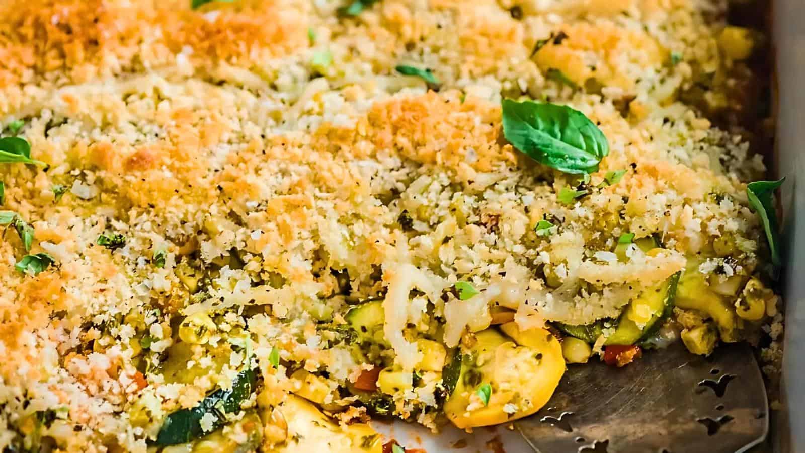 A baked vegetable casserole with a golden brown breadcrumb crust, garnished with fresh basil leaves.