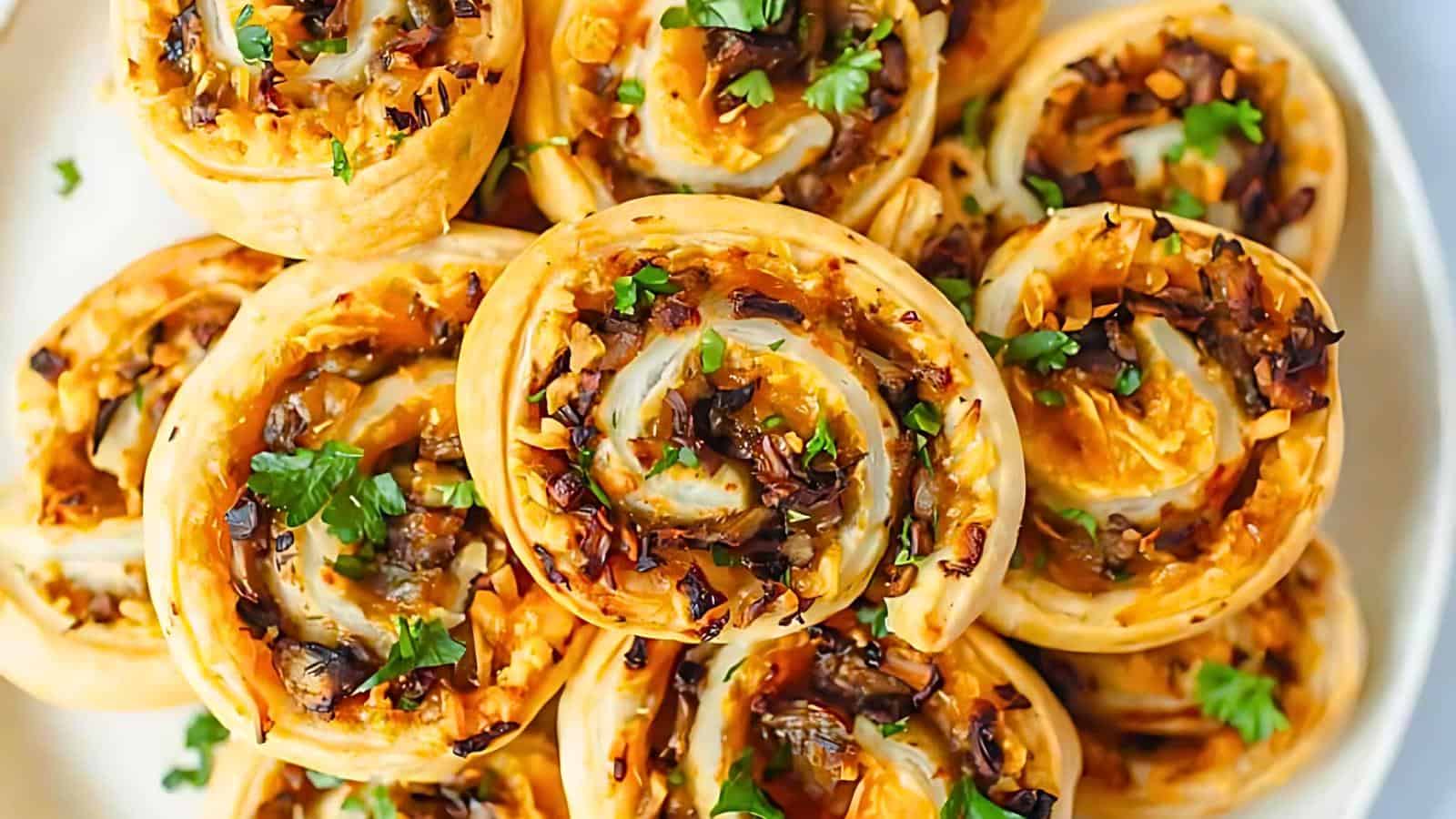 A plate of pinwheel pastries garnished with fresh parsley, featuring golden-brown swirled dough filled with caramelized onions and cheese.
