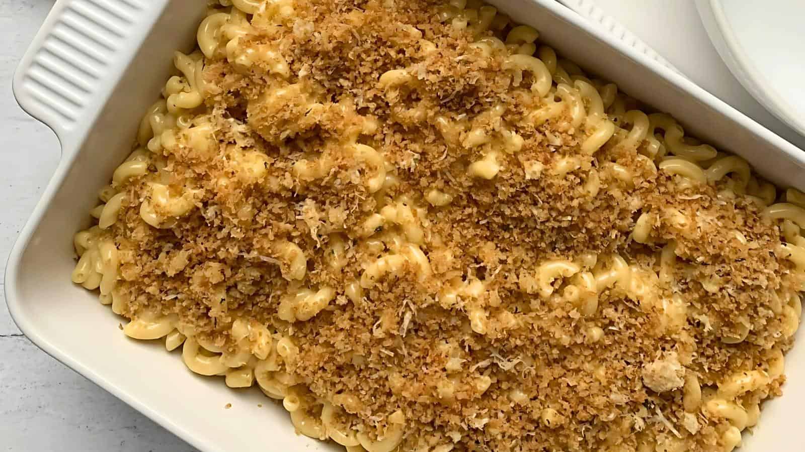 A rectangular baking dish filled with macaroni and cheese topped with a golden breadcrumb crust.
