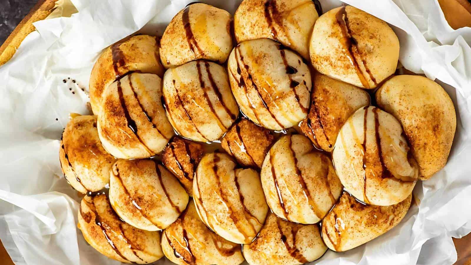 A plate of sliced roasted eggplant drizzled with balsamic glaze on parchment paper. The slices are evenly arranged and appear golden brown with caramelized edges.