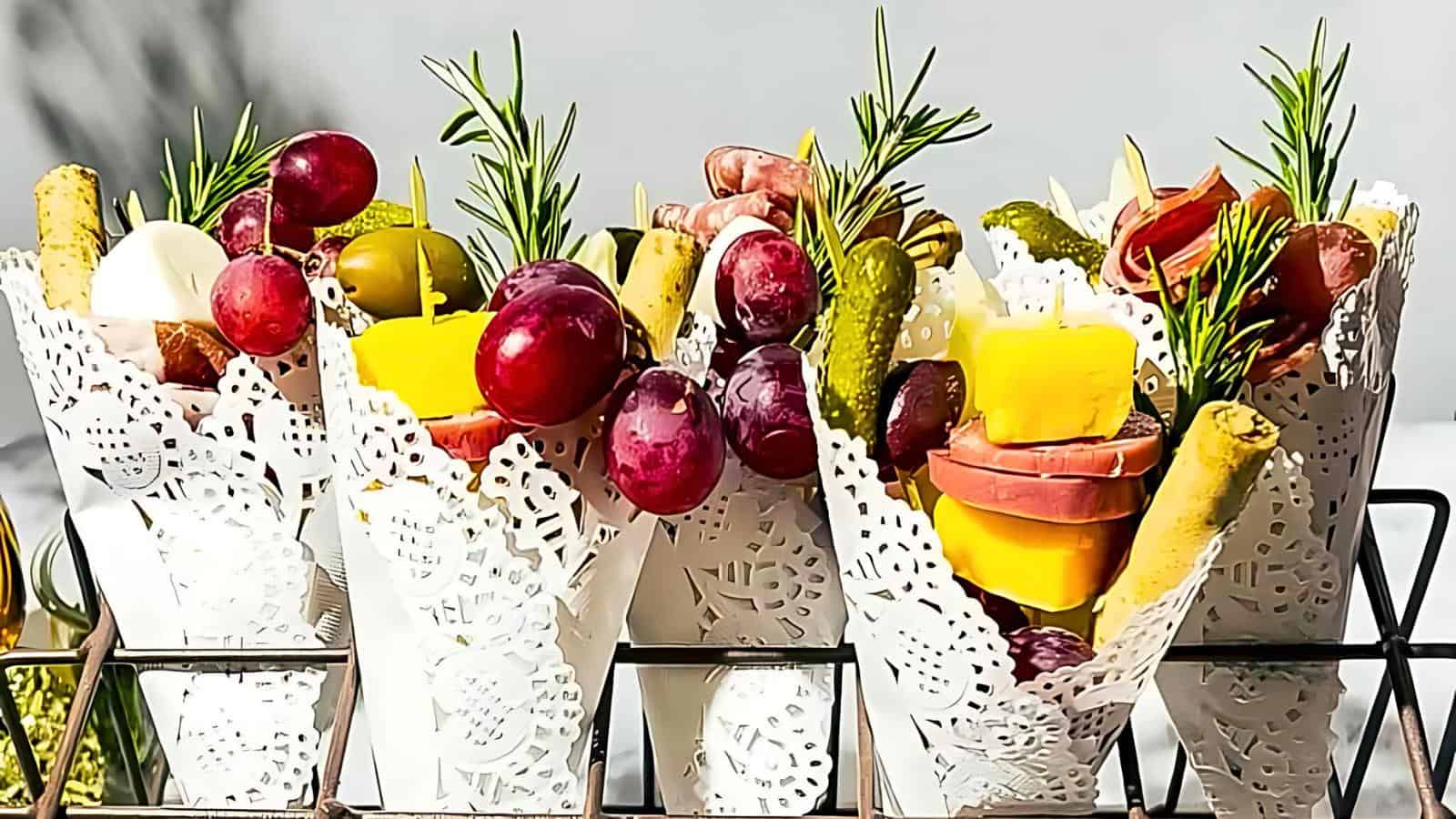 Decorative cones filled with grapes, cheese, pickles, cured meats, and sprigs of rosemary.