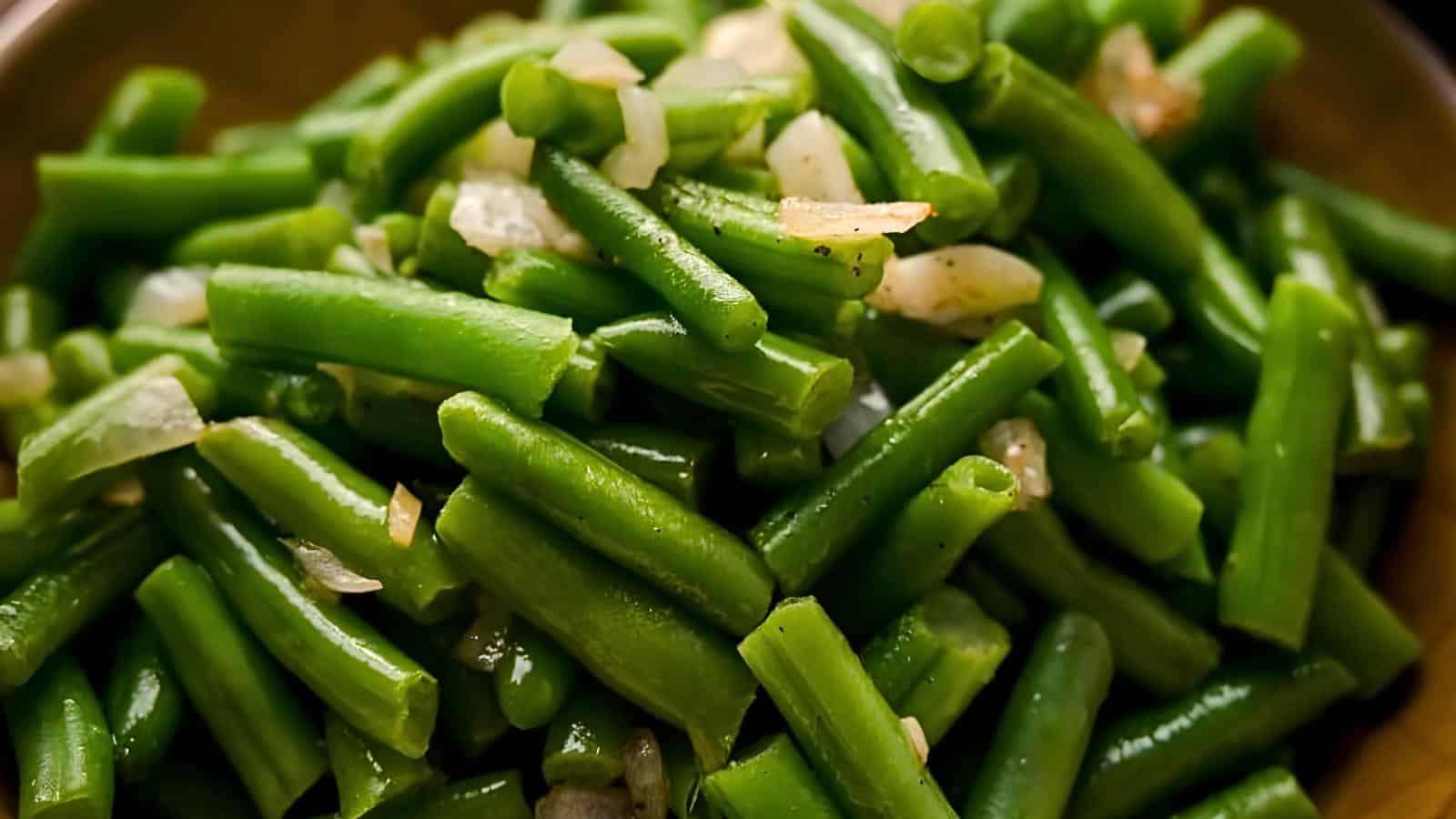 A close-up of chopped, cooked green beans mixed with small pieces of onion.