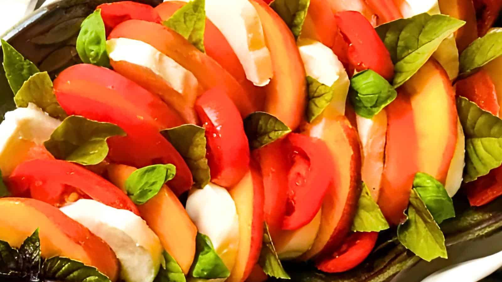 Slices of tomatoes, mozzarella cheese, and fresh basil leaves arranged in an alternating pattern on a platter.