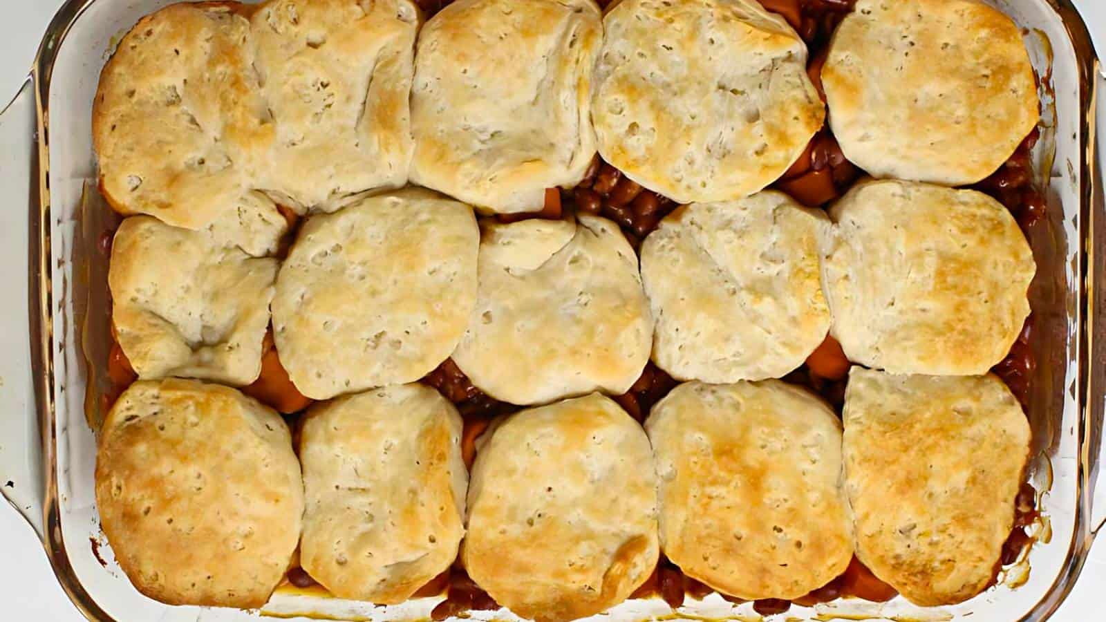 A baking dish with a baked casserole topped with golden brown biscuits.