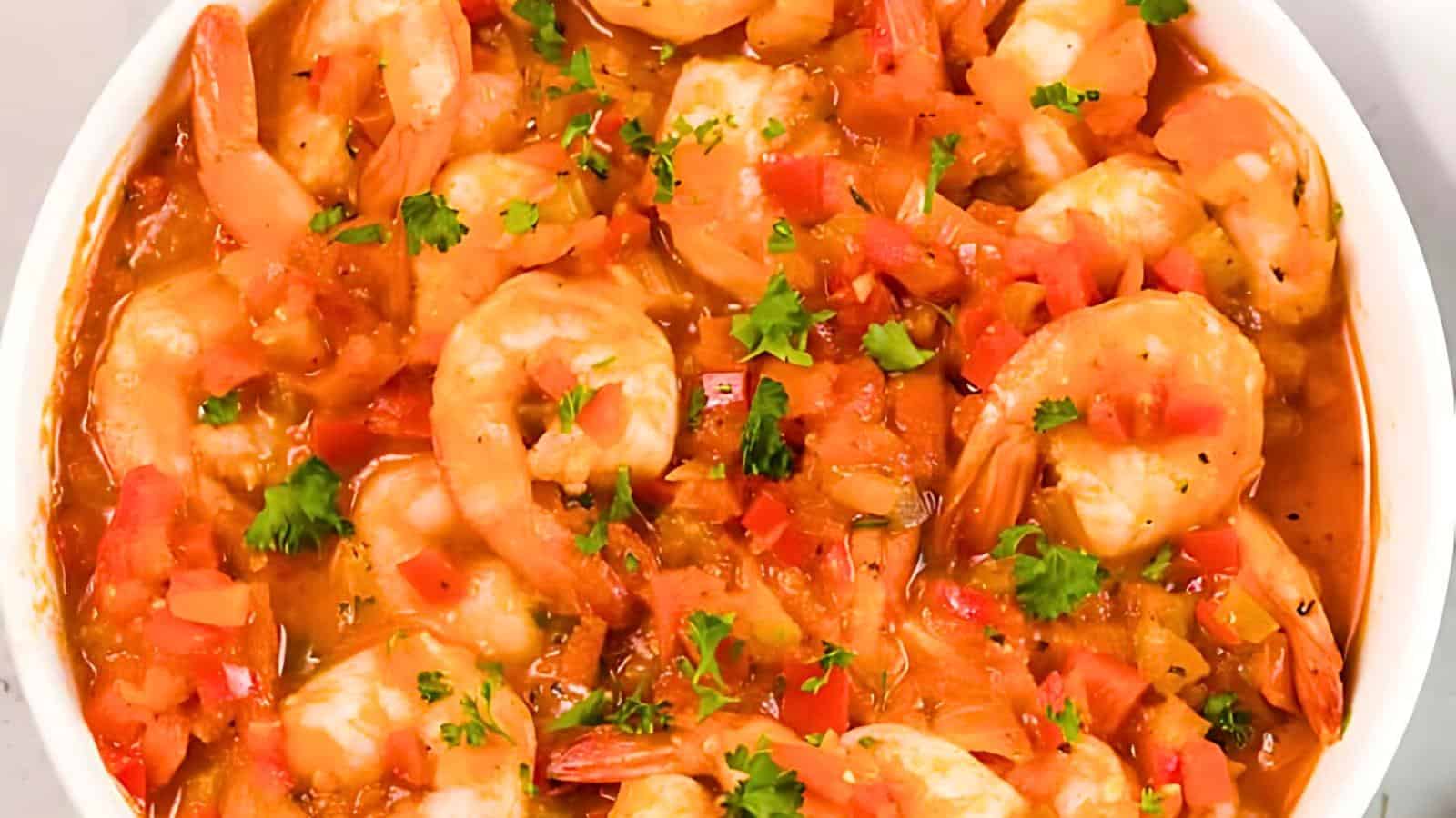 A bowl with shrimp in a tomato-based sauce, garnished with chopped parsley.
