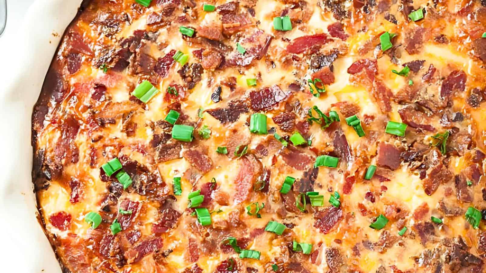 A freshly baked quiche, topped with crispy bacon pieces and chopped green onions.