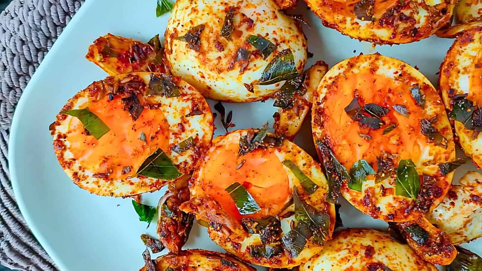 Halved hard-boiled eggs, spiced and garnished, arranged on a white plate.