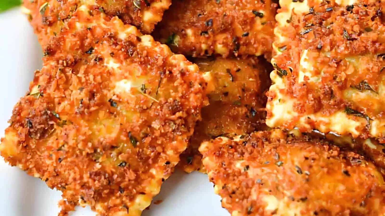 Golden and crispy breaded ravioli with visible herbs and textured breading.