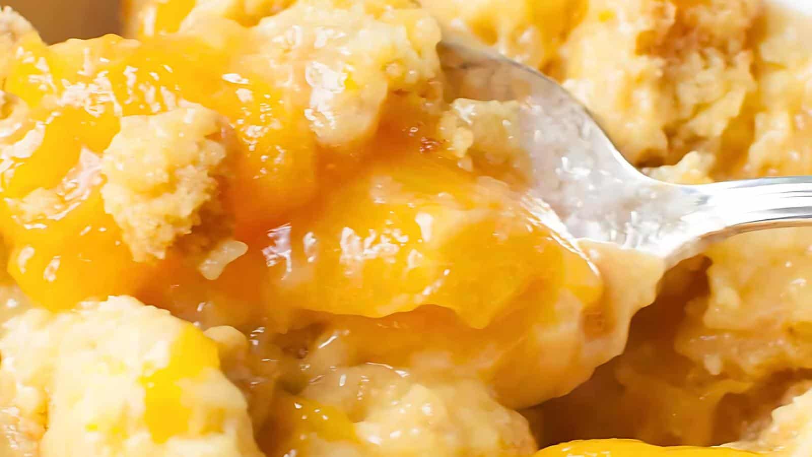 A spoonful of peach cobbler with visible chunks of peaches and a crumbly topping.