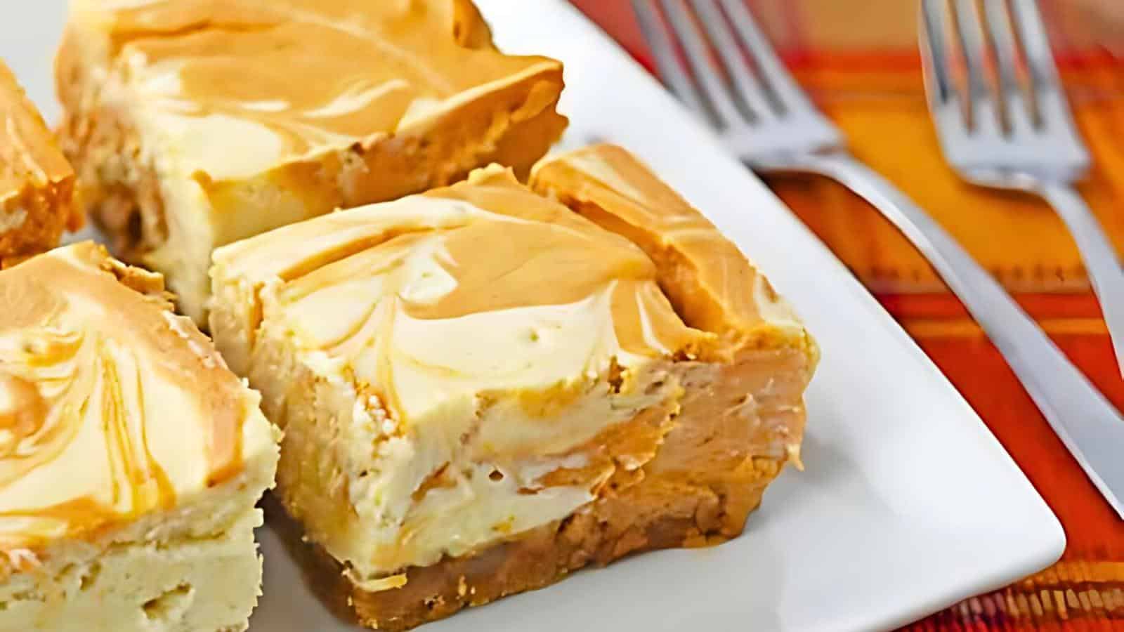 Close-up of a plate with slices of cheesecake featuring a caramel swirl on top. Two forks are placed beside the plate on a table with a colorful checkered tablecloth.
