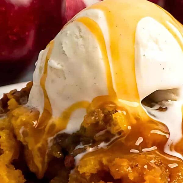A scoop of vanilla ice cream topped with caramel sauce, sitting on a bed of apple crumble.