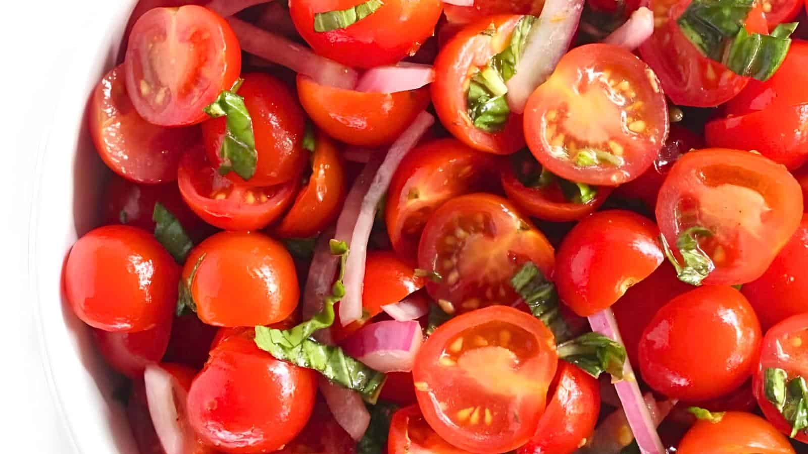 A bowl of cherry tomatoes, sliced red onions, and chopped basil.