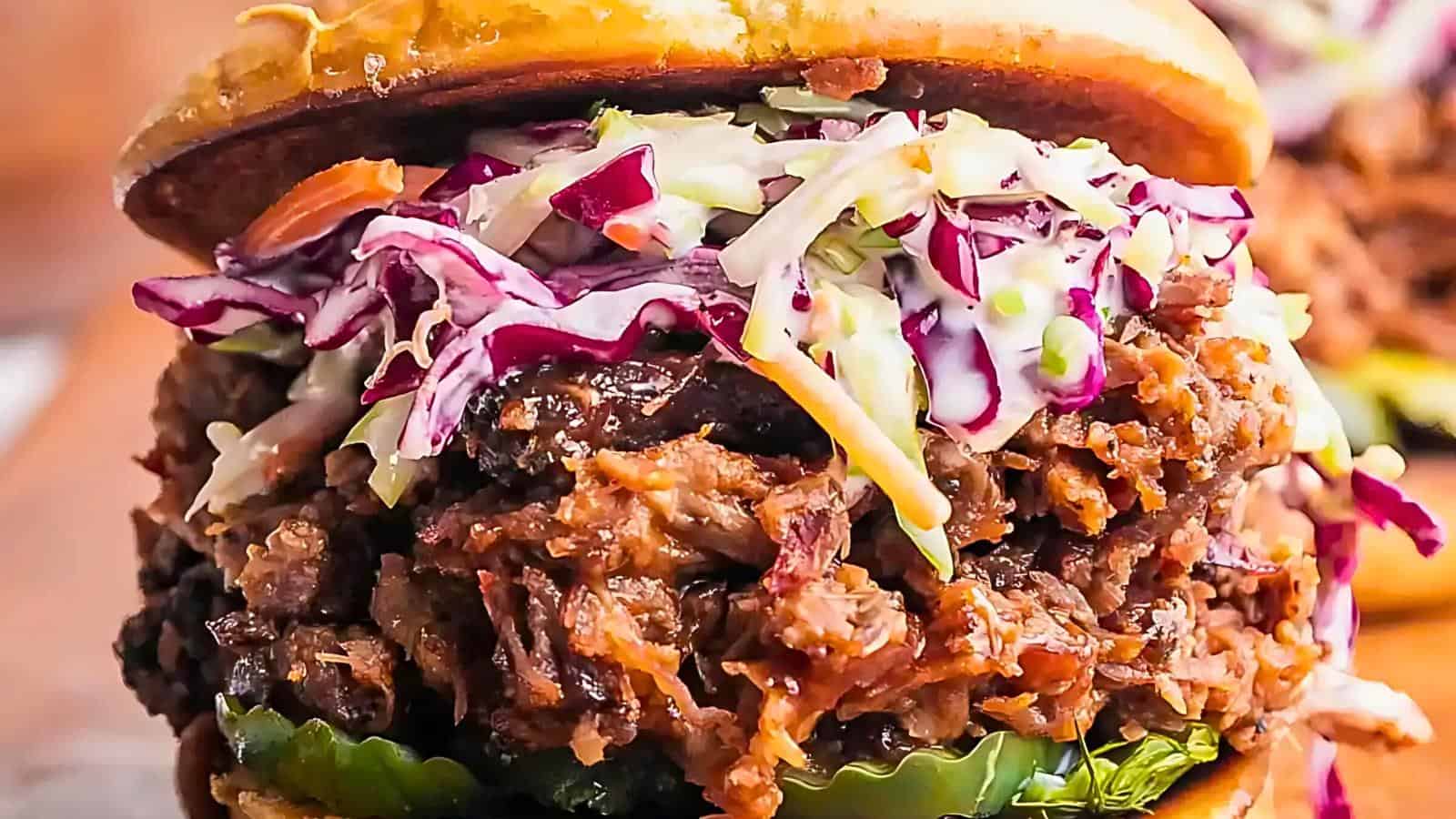 Close-up image of a smoked brisket sandwich with coleslaw and pickles on a bun.