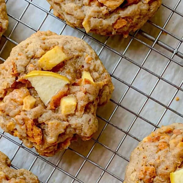 Cookies with apple chunks cooling on a wire rack.