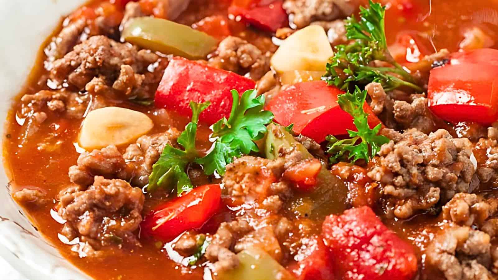 Visible chunks of ground meat, tomatoes, bell peppers, garlic, and parsley garnish.