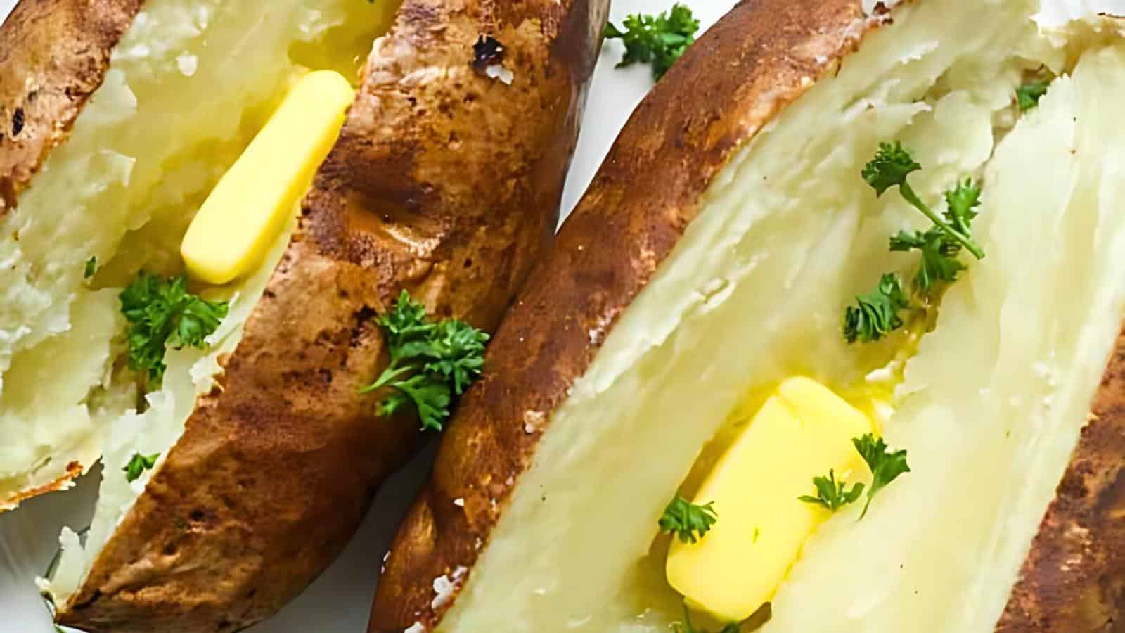 Two baked potatoes split open, each with a pat of melting butter and garnished with fresh parsley.