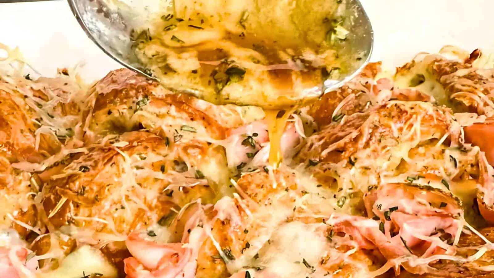 Croissant sandwiches with melted cheese and herbs, being topped with a sauce from a spoon.