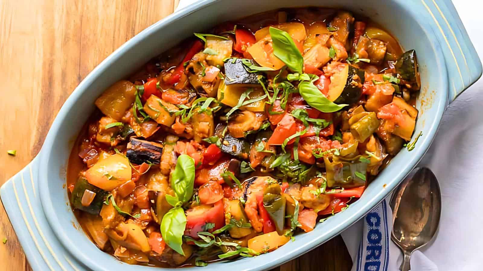 A blue dish containing diced tomatoes, zucchini, and bell peppers, garnished with fresh basil leaves.