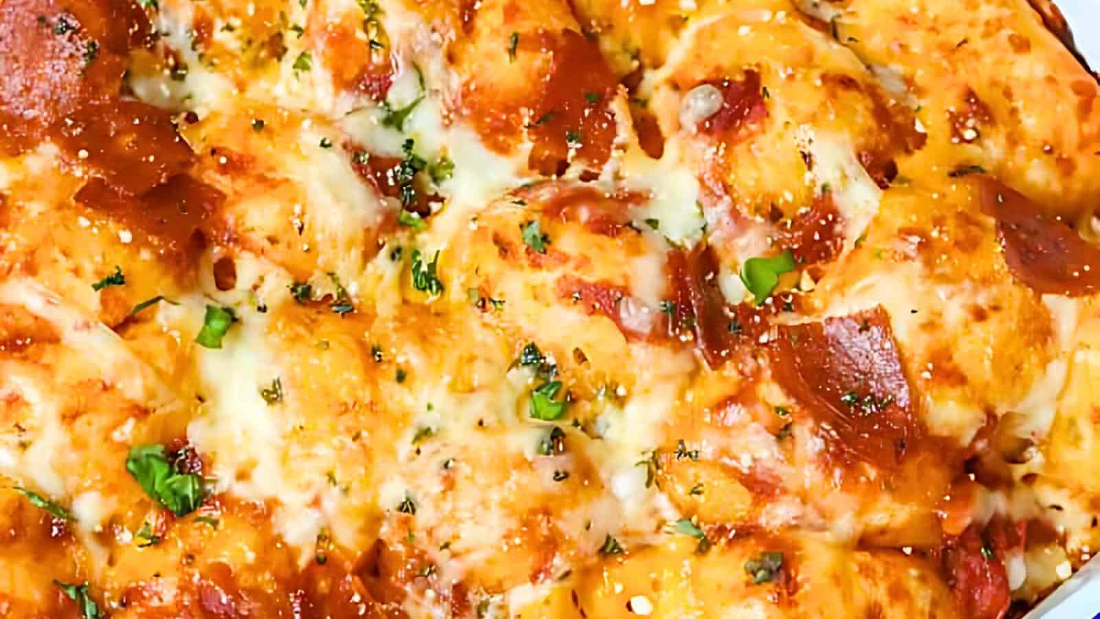 Close-up of a golden-brown, cheesy baked dish topped with melted cheese, pepperoni slices, and sprinkled with herbs and green garnishes.