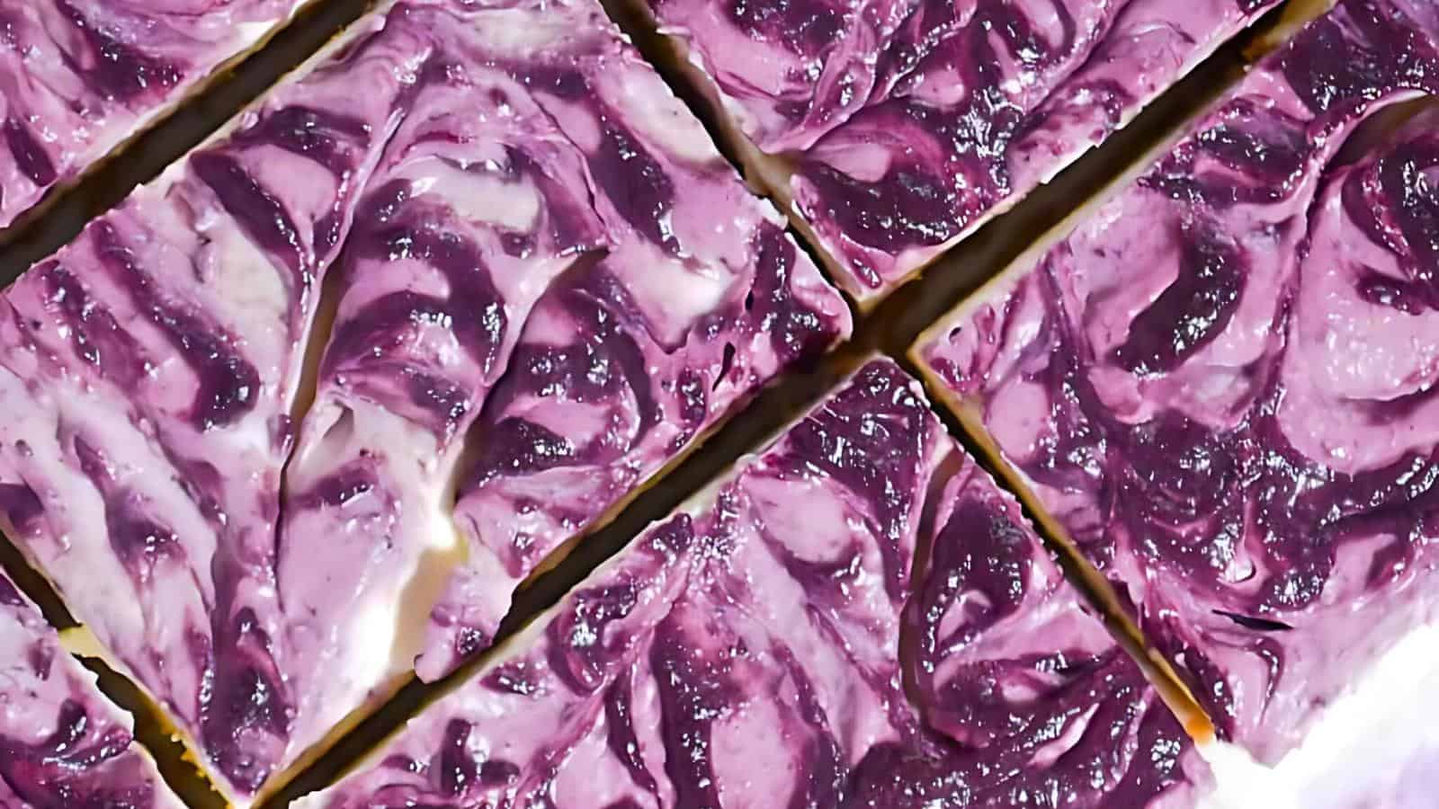 Six cheesecake bars arranged in a grid pattern, featuring a purple and white marbled topping.