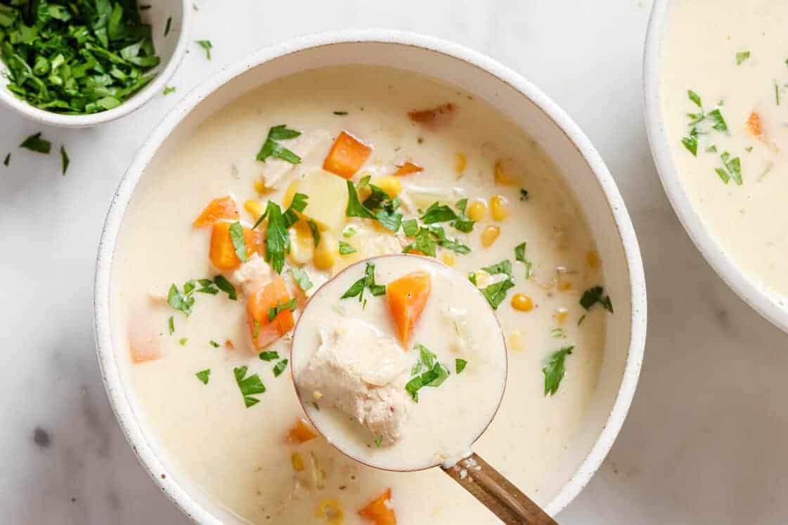 Two bowls of chicken corn soup garnished with parsley.
