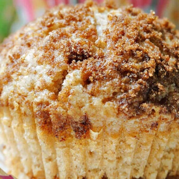 A sweet muffin in a paper liner, topped with crumbly brown sugar and cinnamon streusel.
