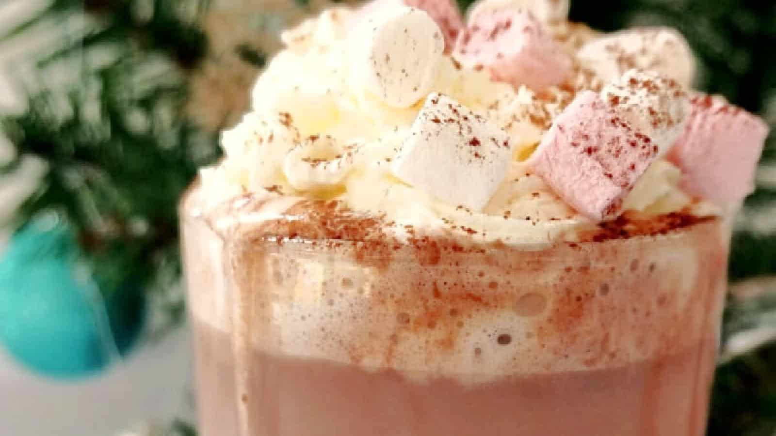 A glass with hot chocolate topped with cream and marshmallows.