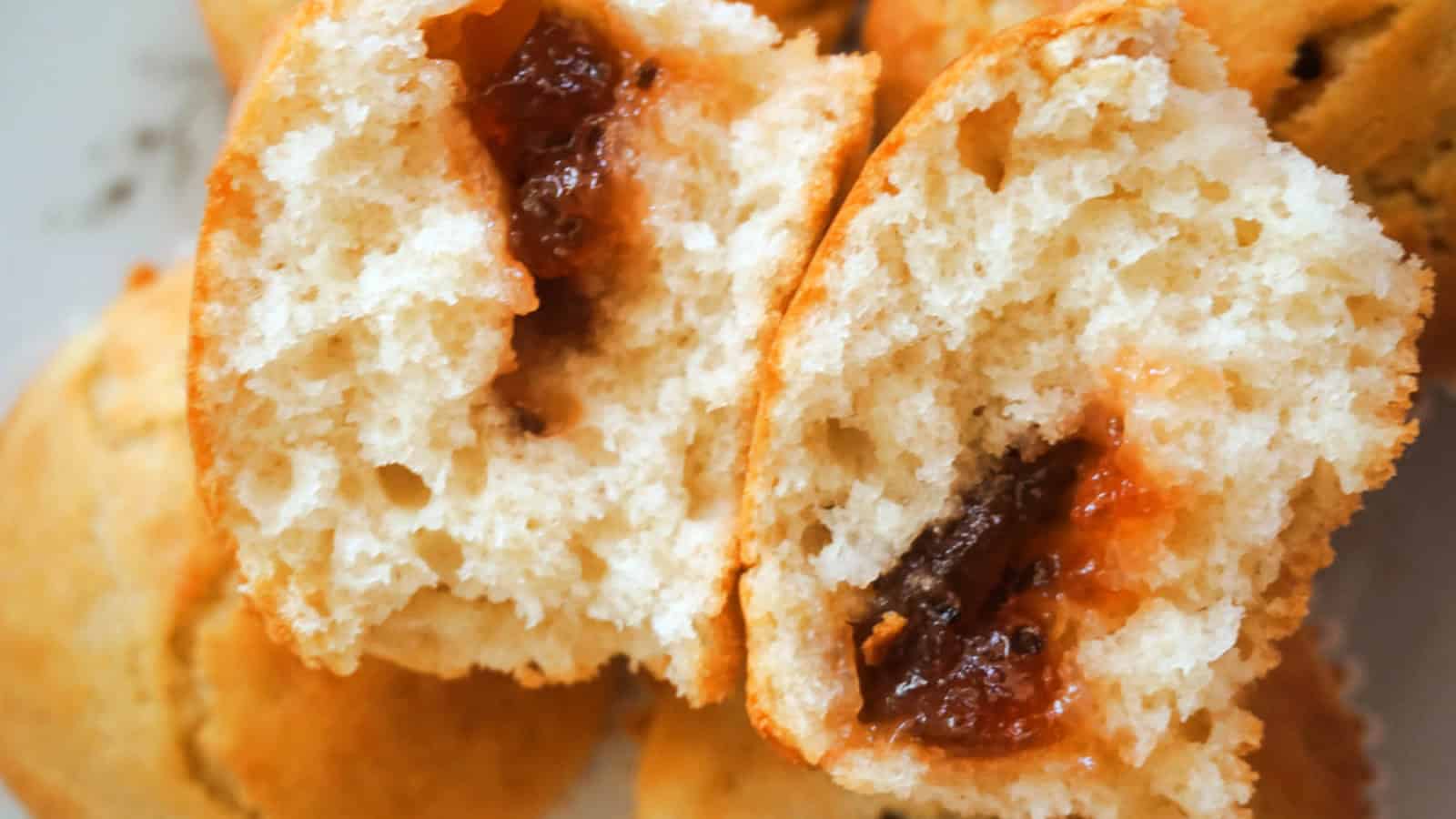 2 halves of a jam muffin on top of other muffins.