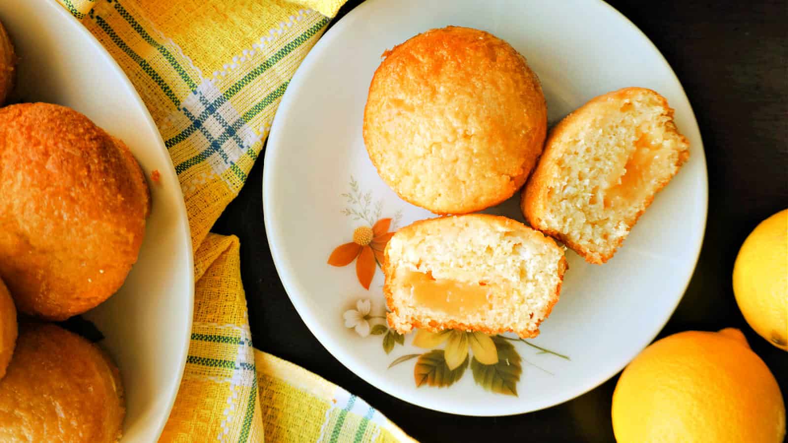 A flowery plate with 2 halves of  a lemon curd muffin and a whole muffin next to them.