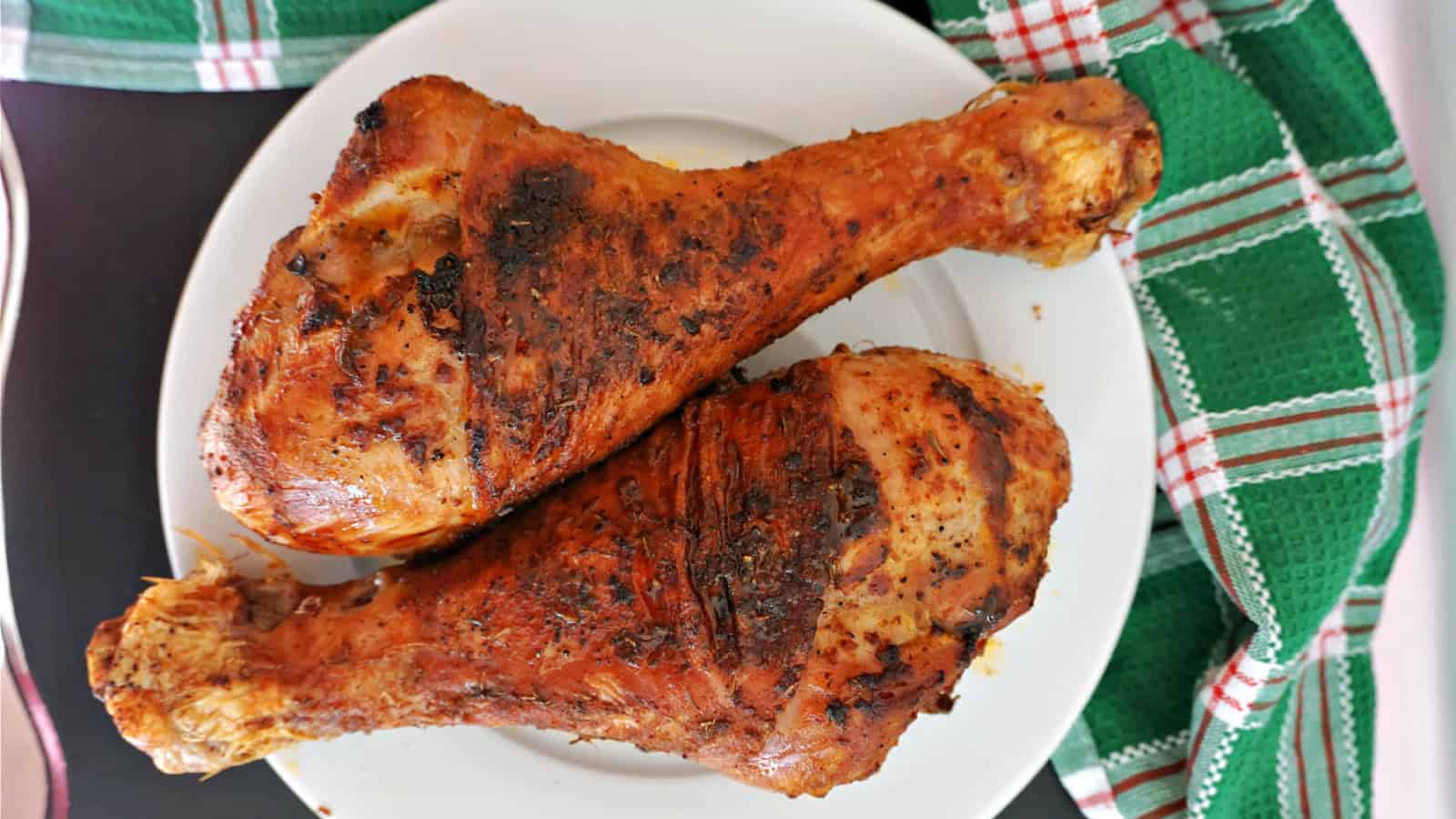 2 roasted turkey drumsticks on a plate.