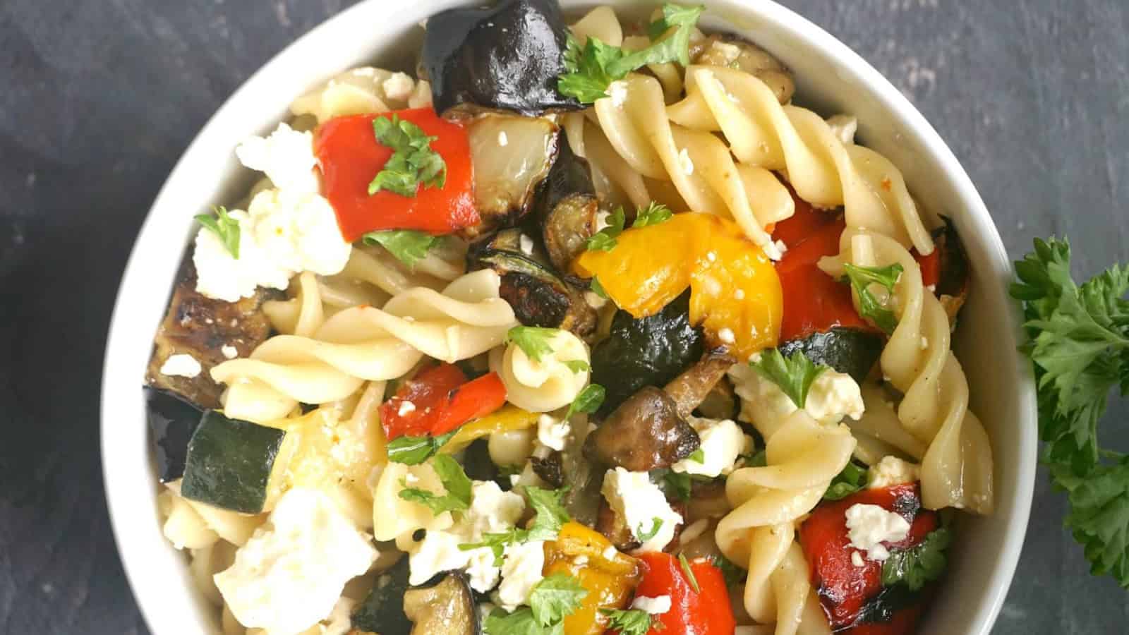 A portion of vegetable pasta salad in a white bowl.