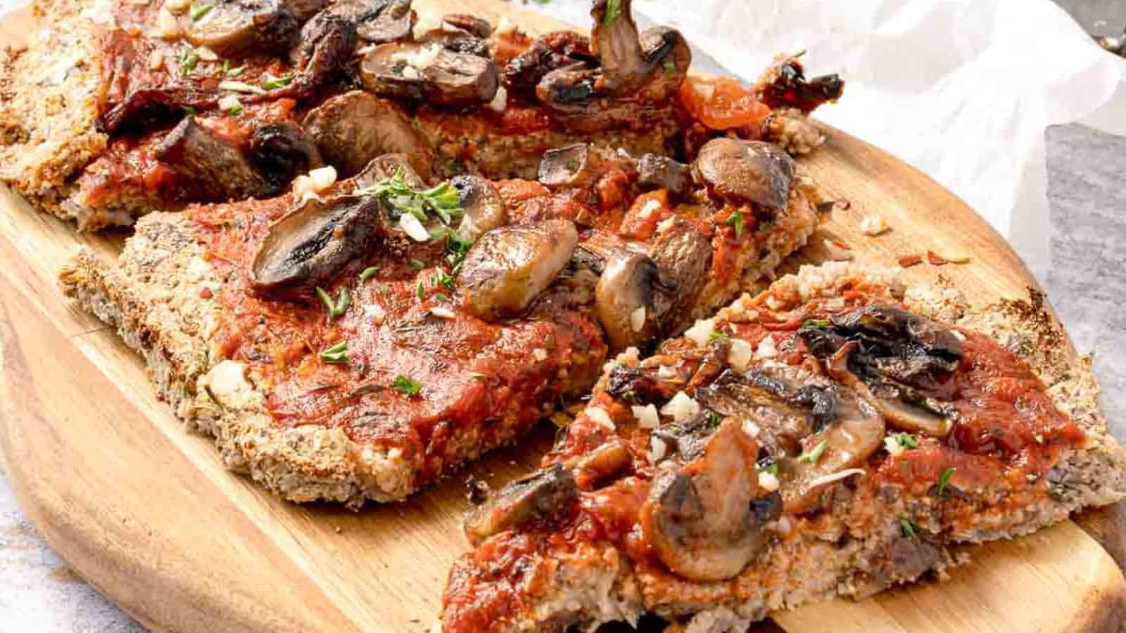 Slices of pizza topped with mushrooms and herbs on a wooden serving board.