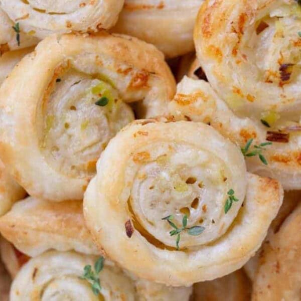 Baked puff pastry pinwheels filled with a savory mixture, topped with herbs and lightly browned.