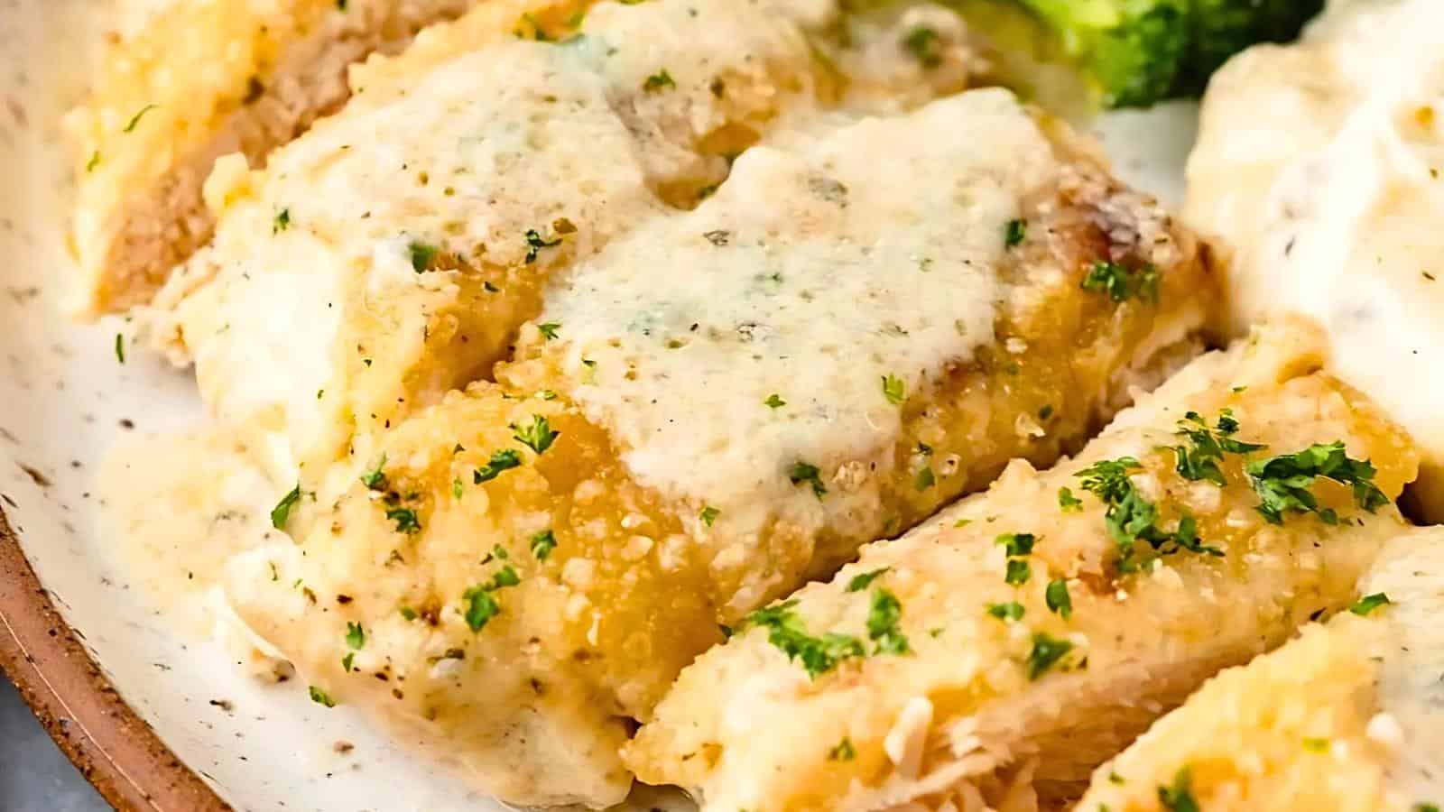 A close-up view of a plate featuring cheesy manicotti sprinkled with herbs and a creamy sauce. The pasta is golden brown and garnished with finely chopped parsley. Broccoli florets are visible in the background, adding a pop of green to the dish.
