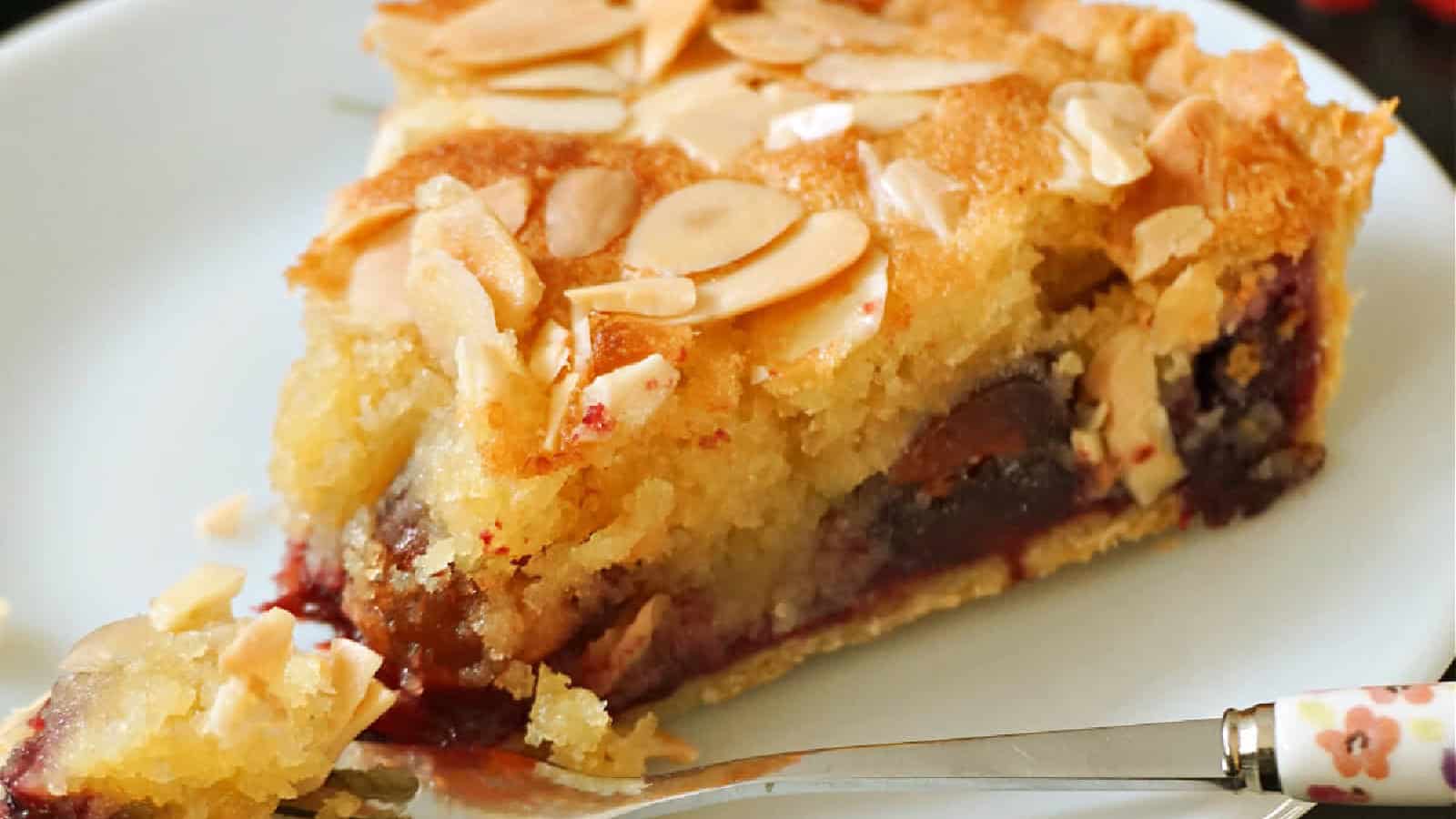 A slice of cherry bakewell on a white.