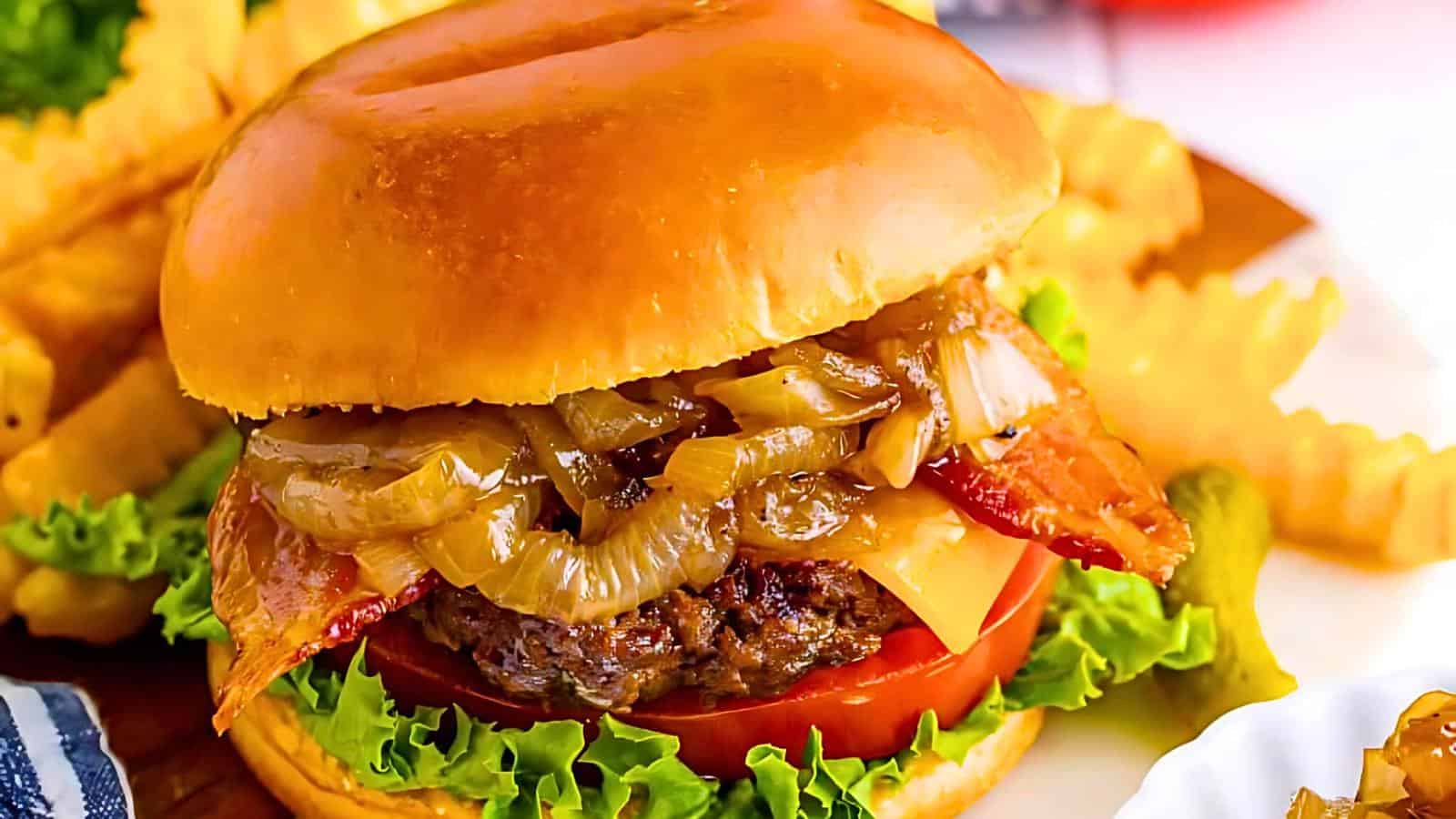 A close-up of a juicy burger with caramelized onions, crispy bacon, melted cheese, lettuce, and a slice of tomato, all encased in a soft, golden bun. Crinkle-cut fries and a pickle are in the background, completing the delicious meal.
