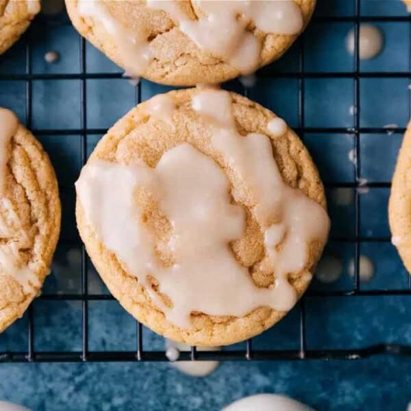Sweet glazed cookies on a cooling rack with drips of maple glaze on the blue surface below.