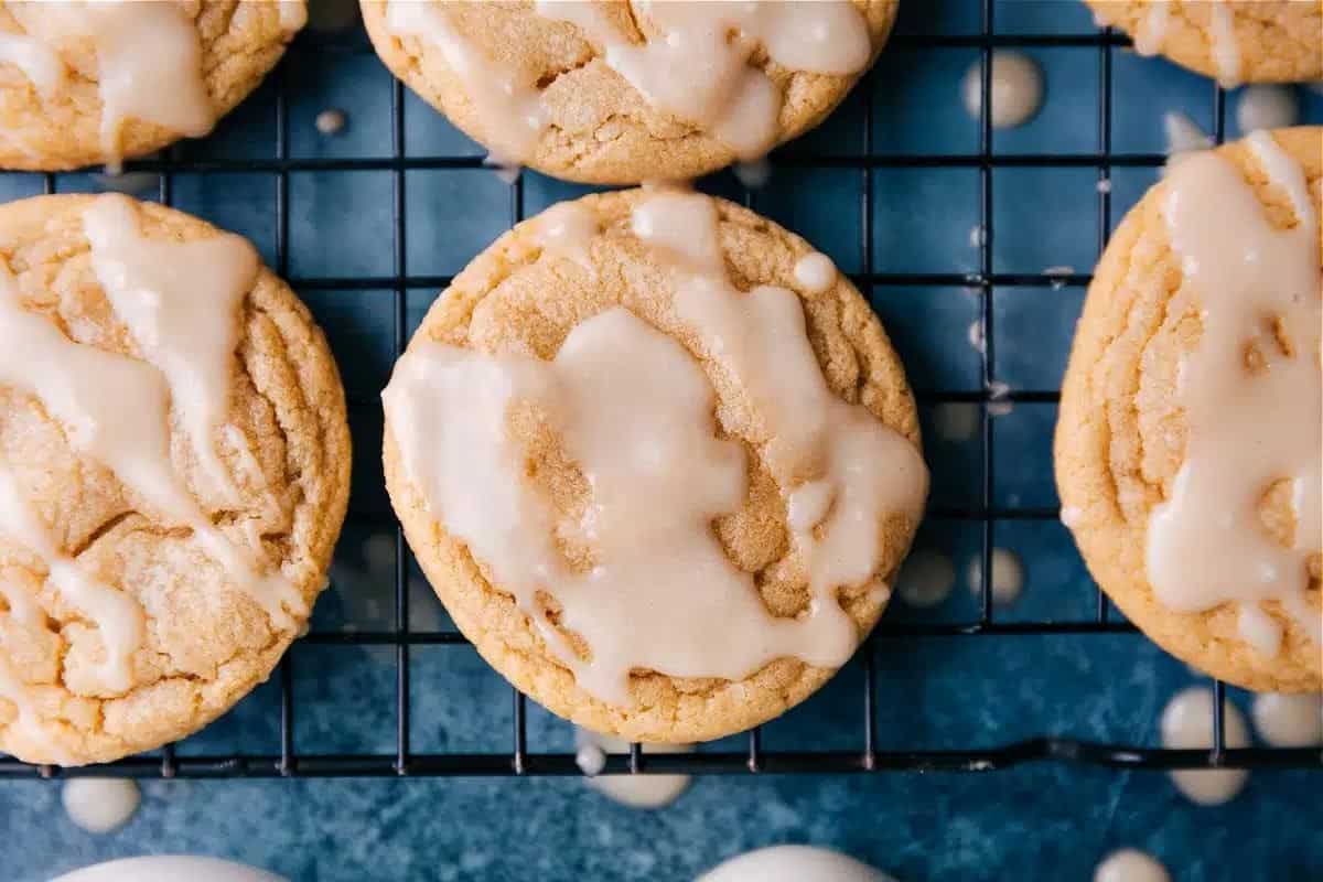 Sweet glazed cookies on a cooling rack with drips of maple glaze on the blue surface below.