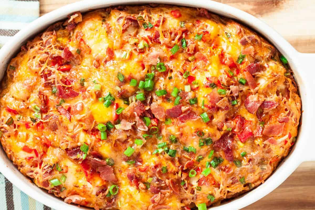 A large baking dish filled with pull apart bread that has cheese and bacon on it.