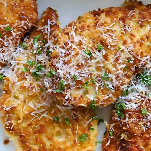 Golden breaded chicken cutlets topped with grated parmesan and chopped parsley, served with lemon wedges on the side.