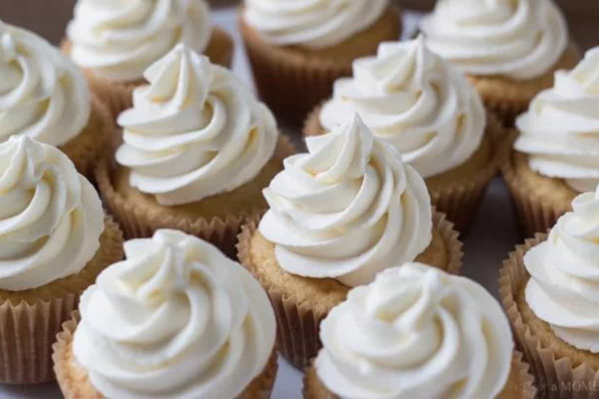 A group of vanilla cupcakes topped with swirls of white frosting.