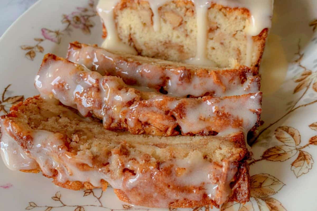 A sliced loaf of bread with white glaze, placed on a floral-patterned plate.