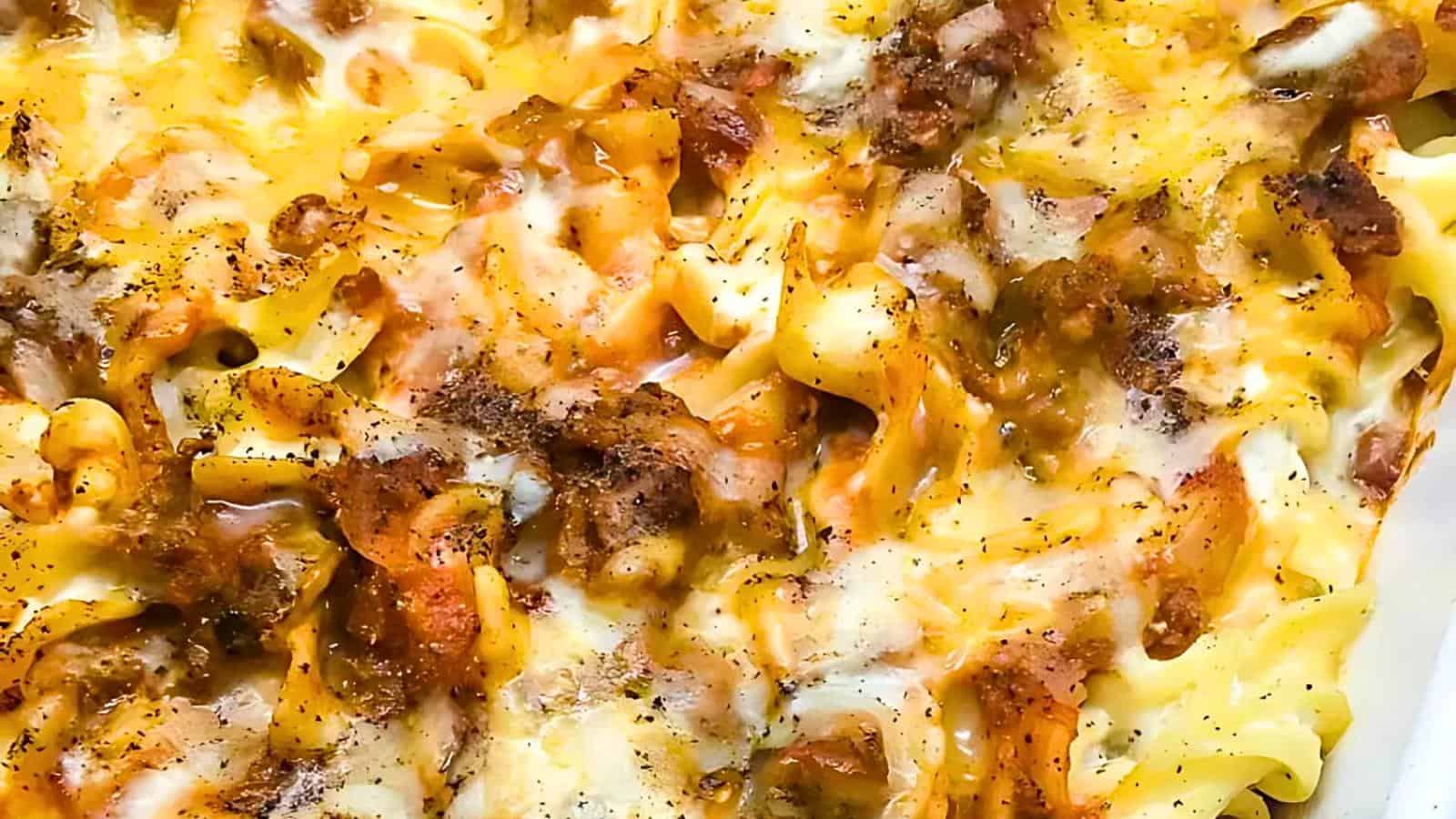 Close-up of a pasta casserole topped with melted cheese, seasoned ground beef, and a sprinkle of black pepper.
