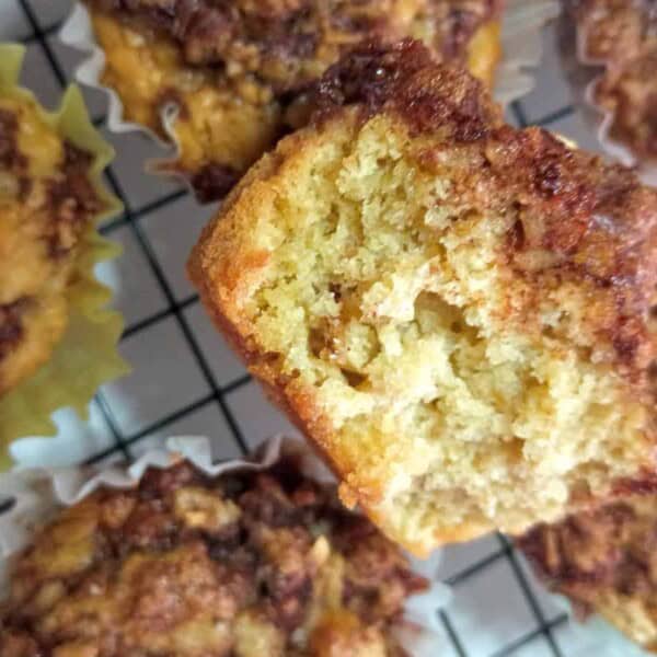 half of a cinnamon swirl muffin in top of others on a cooling rack.