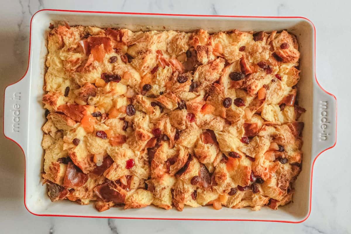 A rectangular baking dish filled with baked bread pudding, topped with pieces of bread and visible raisins.