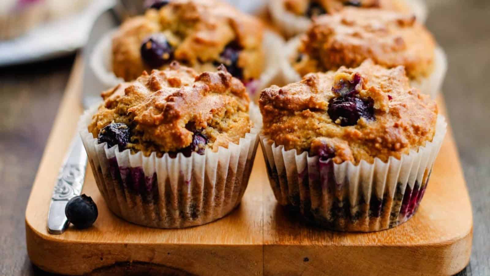 Almond flour blueberry muffins on a wooden chopping board.