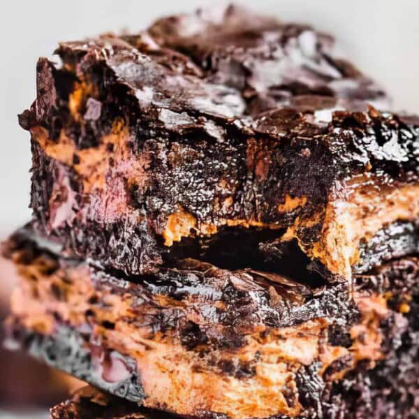 Two stacked chocolate brownies with a rich, gooey texture and a visible layer of chocolate filling in the middle.