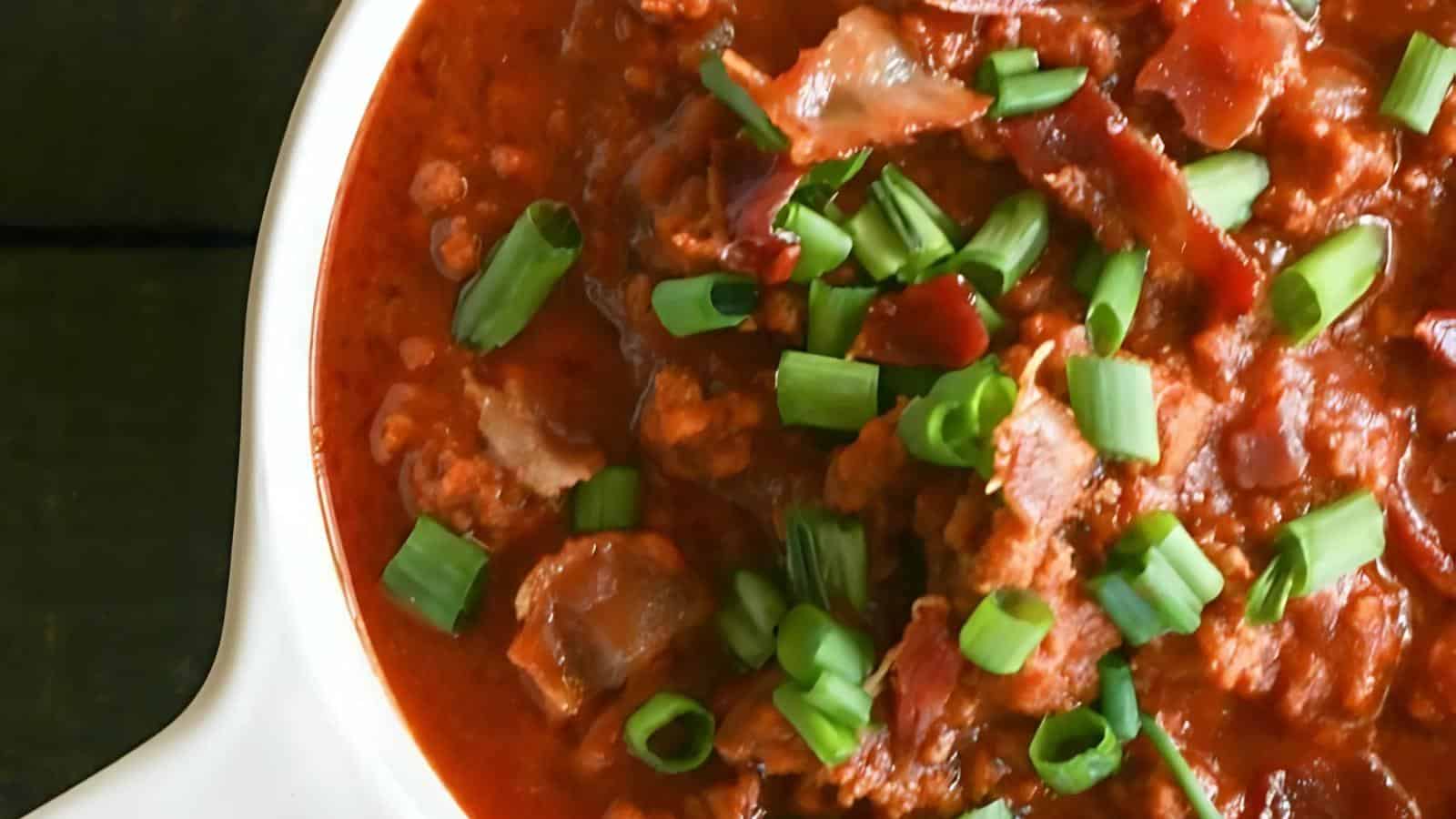 The image shows a bowl of chili garnished with chopped green onions.