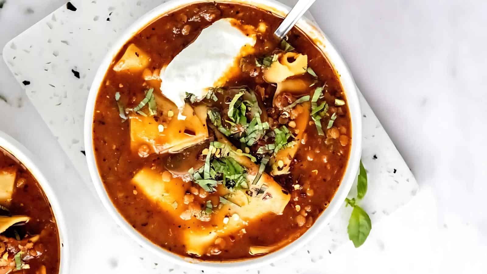 A bowl of soup garnished with herbs and a dollop of cream.